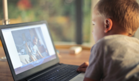 Child seated at desk looking at a computer screen in left profile.