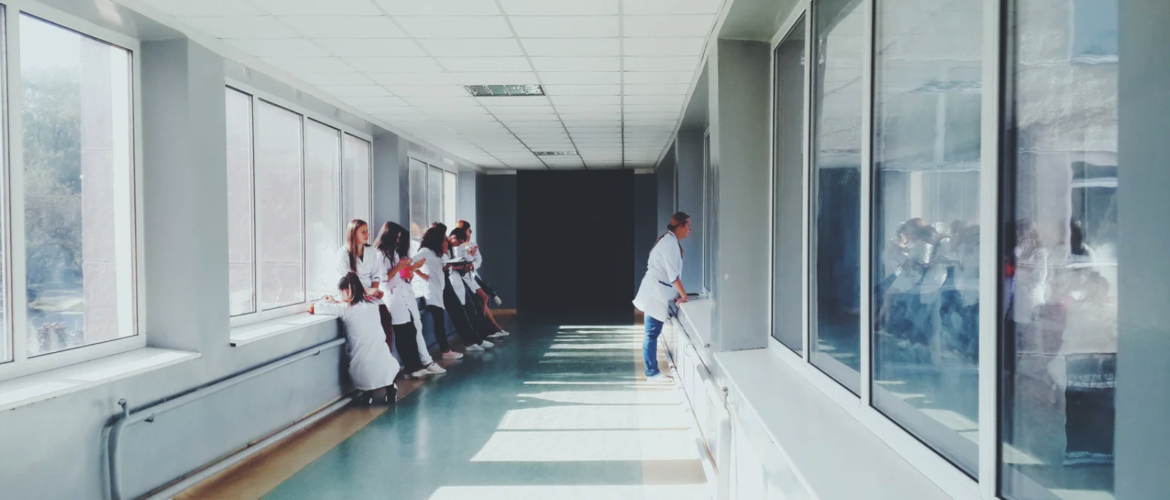 Multiple women standing in long hallway in right side profile.