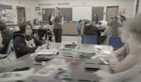 Classroom of children with adult woman standing in the middle.